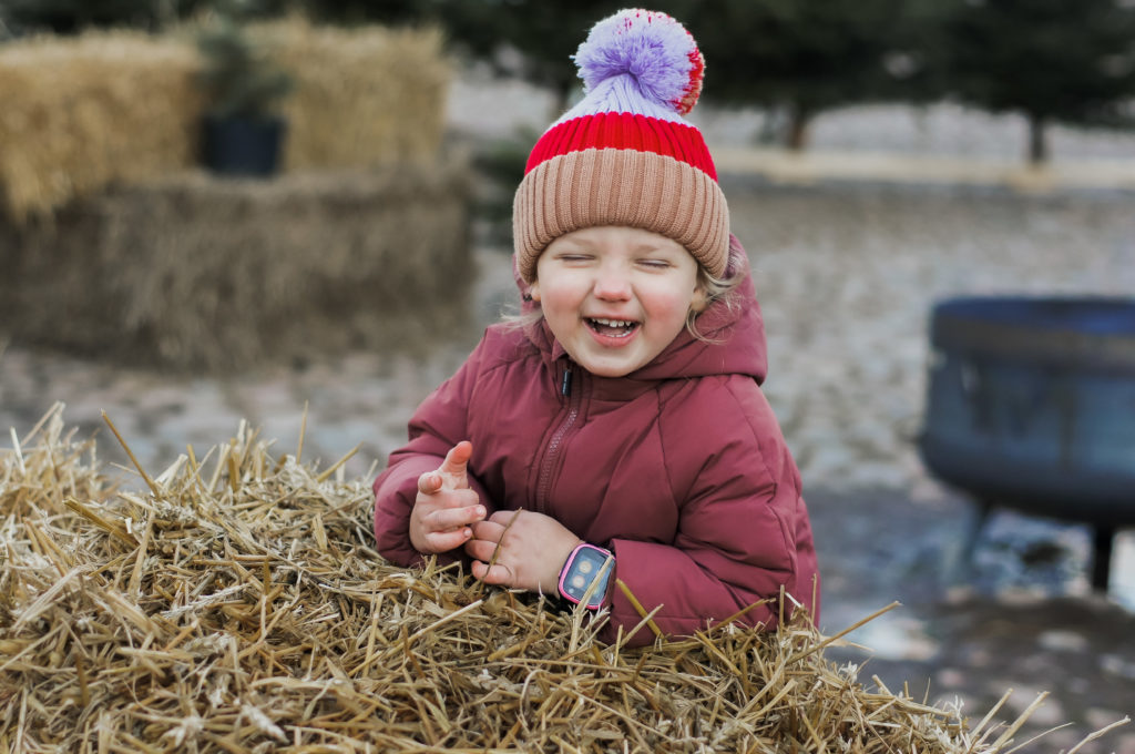 Barn lutar sig mot hö och ler stort